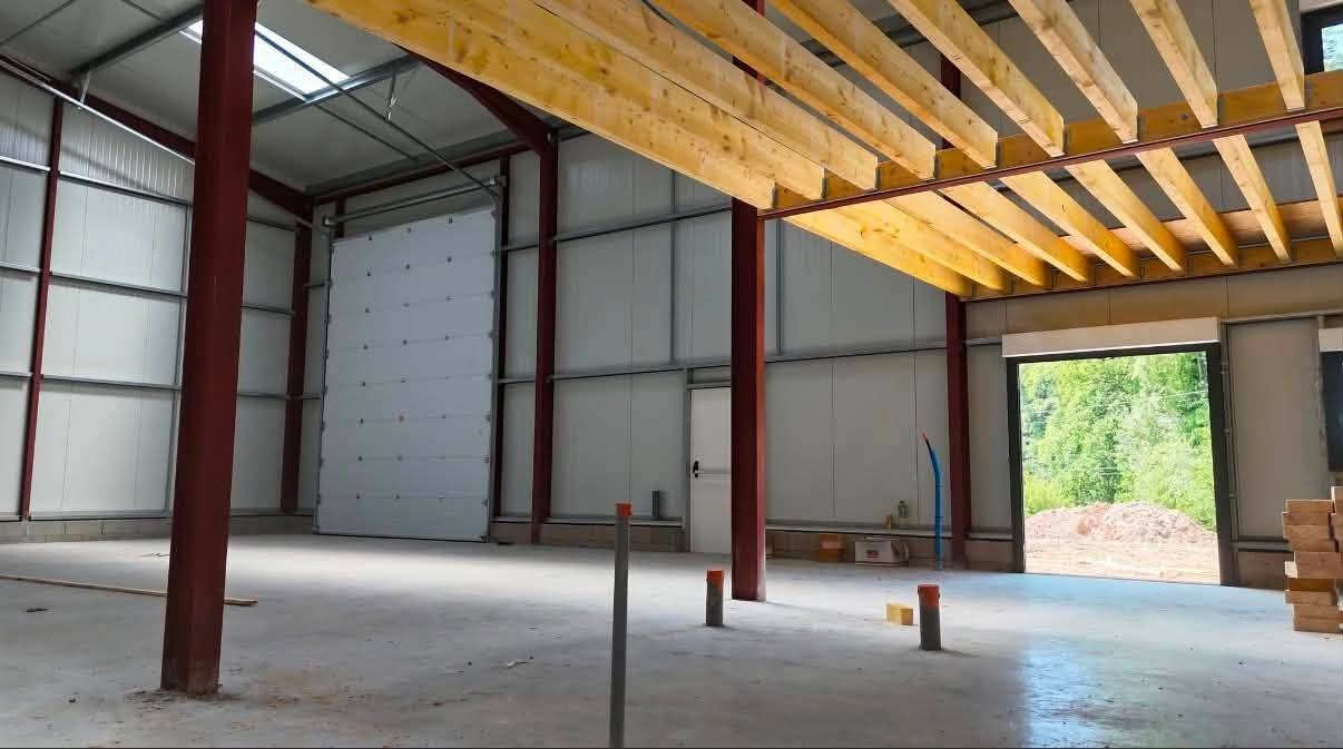 Intérieur d'un bâtiment avec charpente bois de mezzanine et poteaux métalliques