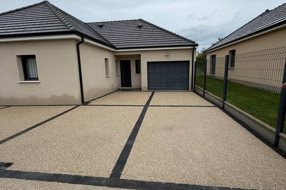 Cour en béton désactivé bordée de pavés devant un garage