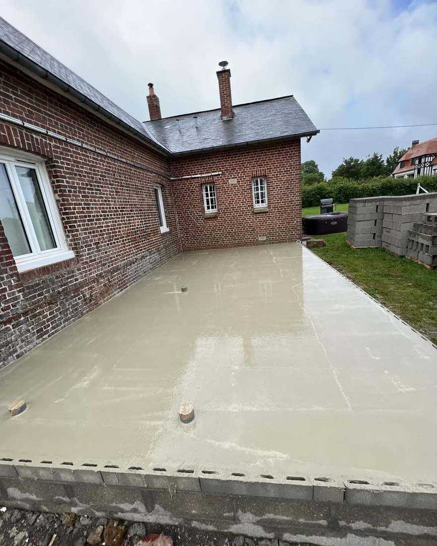 Dalle béton de l'extension coulée à l'intérieur du soubassement, contre la maison en brique