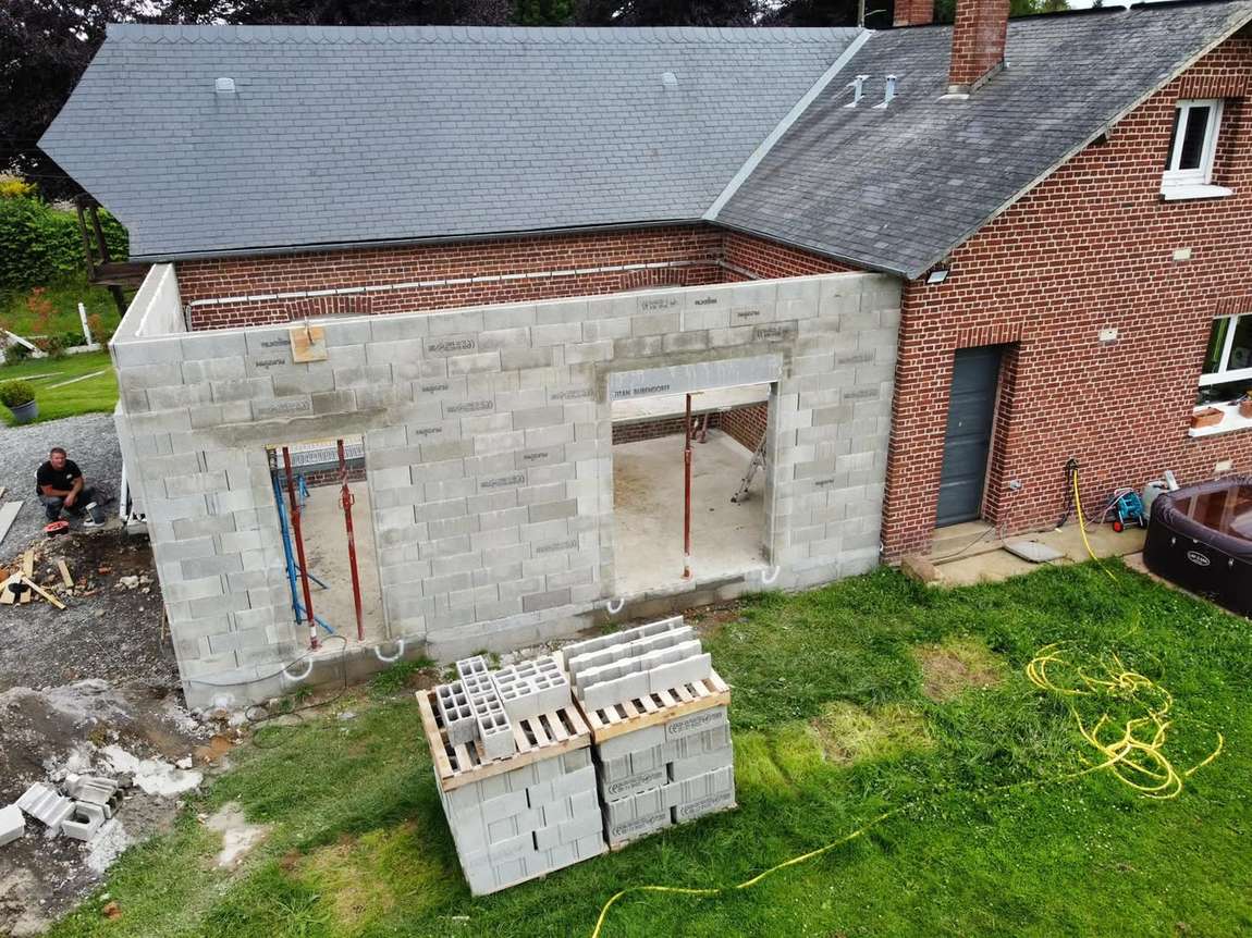 Murs en blocs d'une extension de maison, montés contre une façade en brique