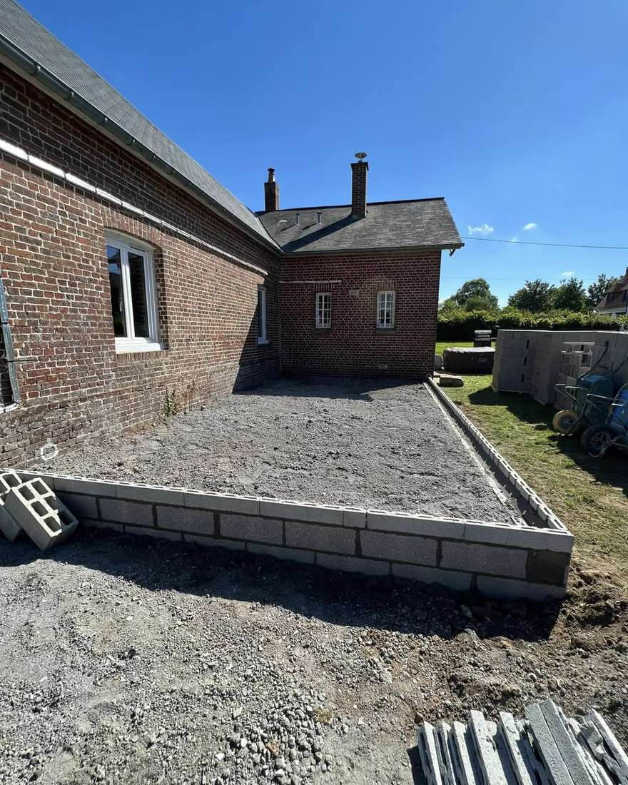 Soubassement en blocs de l'extension, rempli de gravier le long de la maison en brique