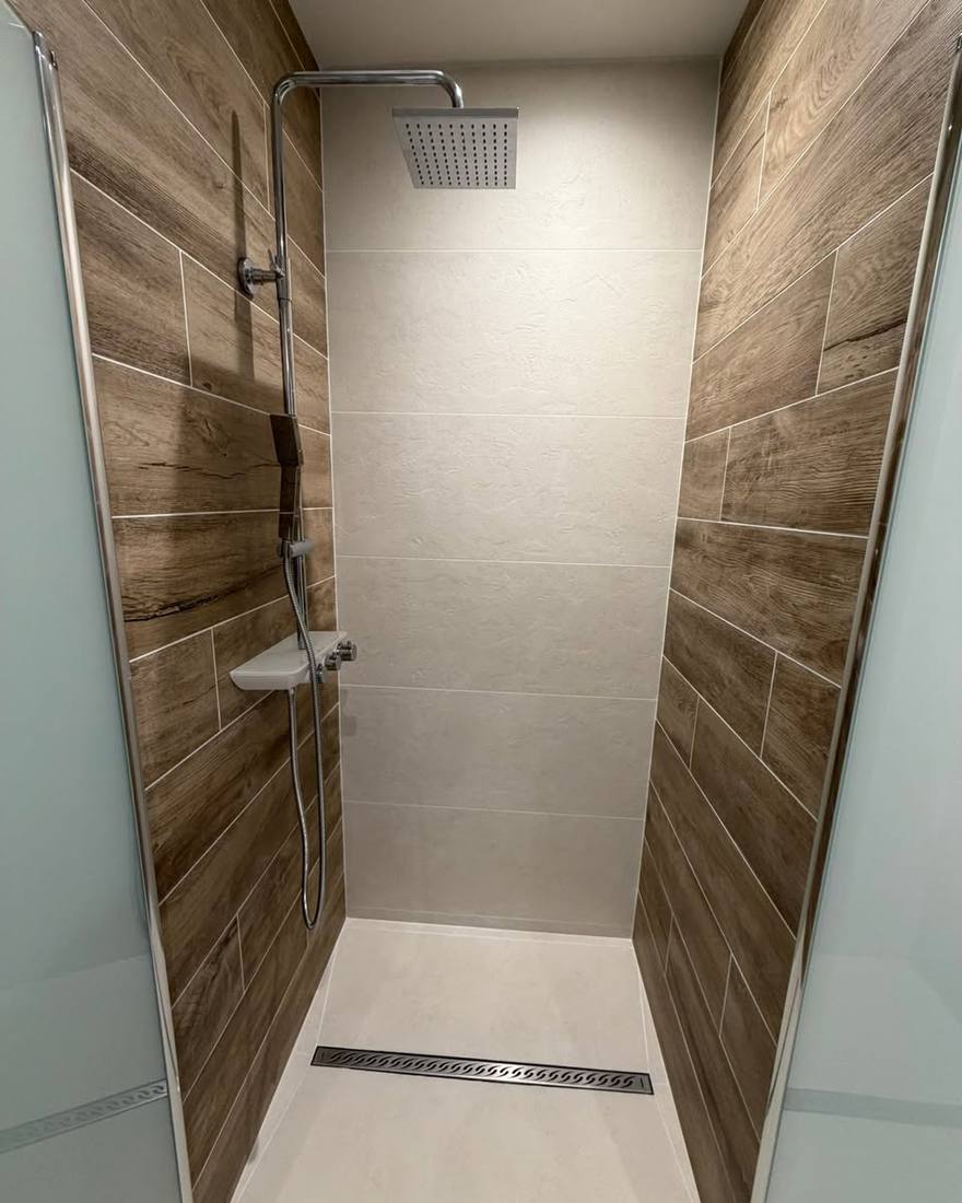 Douche à l'italienne carrelée : grands carreaux effet bois sur les côtés, caniveau linéaire et paroi en verre dépoli