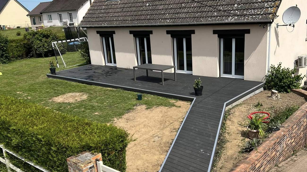 Terrasse en lames composite anthracite et rampe d'accès devant une maison, réalisées par BAT & CO Construction