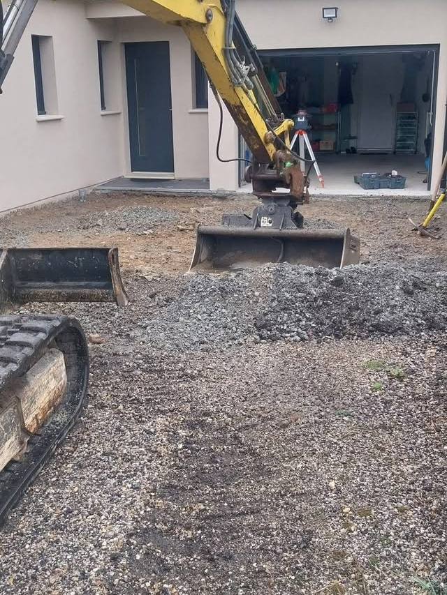 Mini-pelle en cours de terrassement devant une maison neuve
